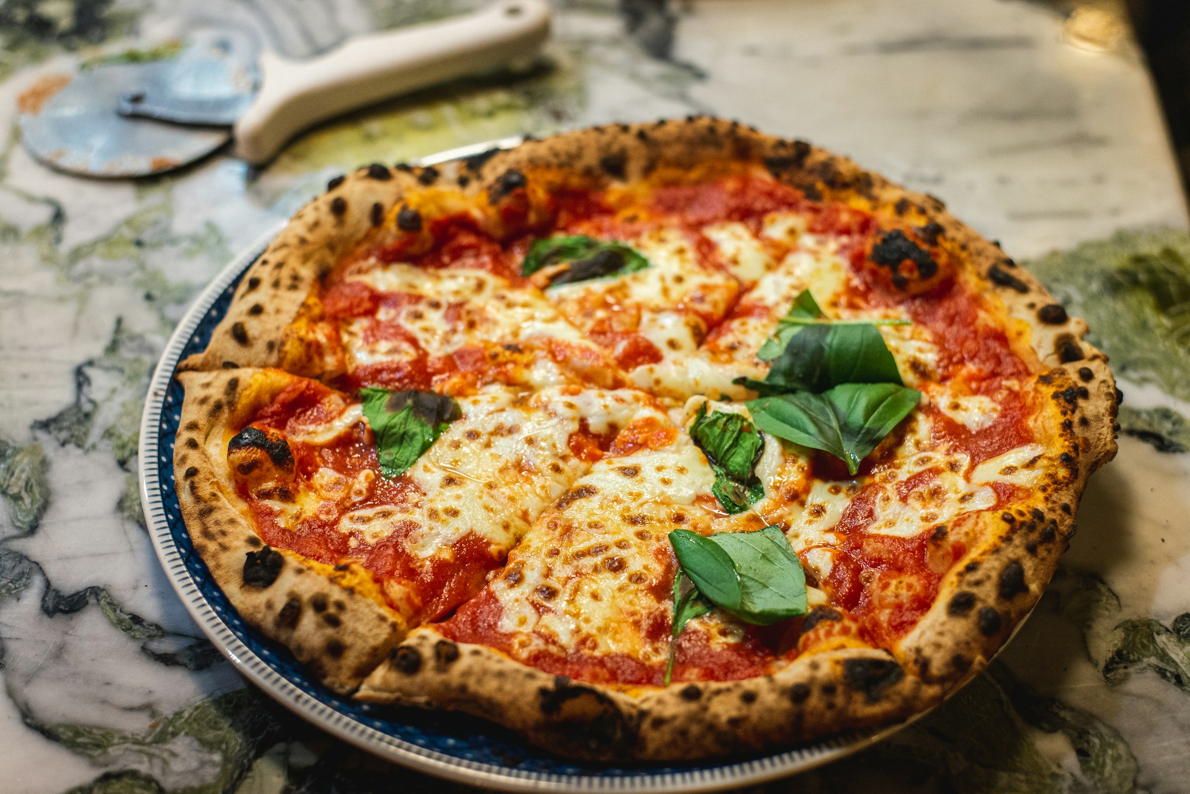 Frisch gebackene Pizza Margherita auf heller Marmorplatte